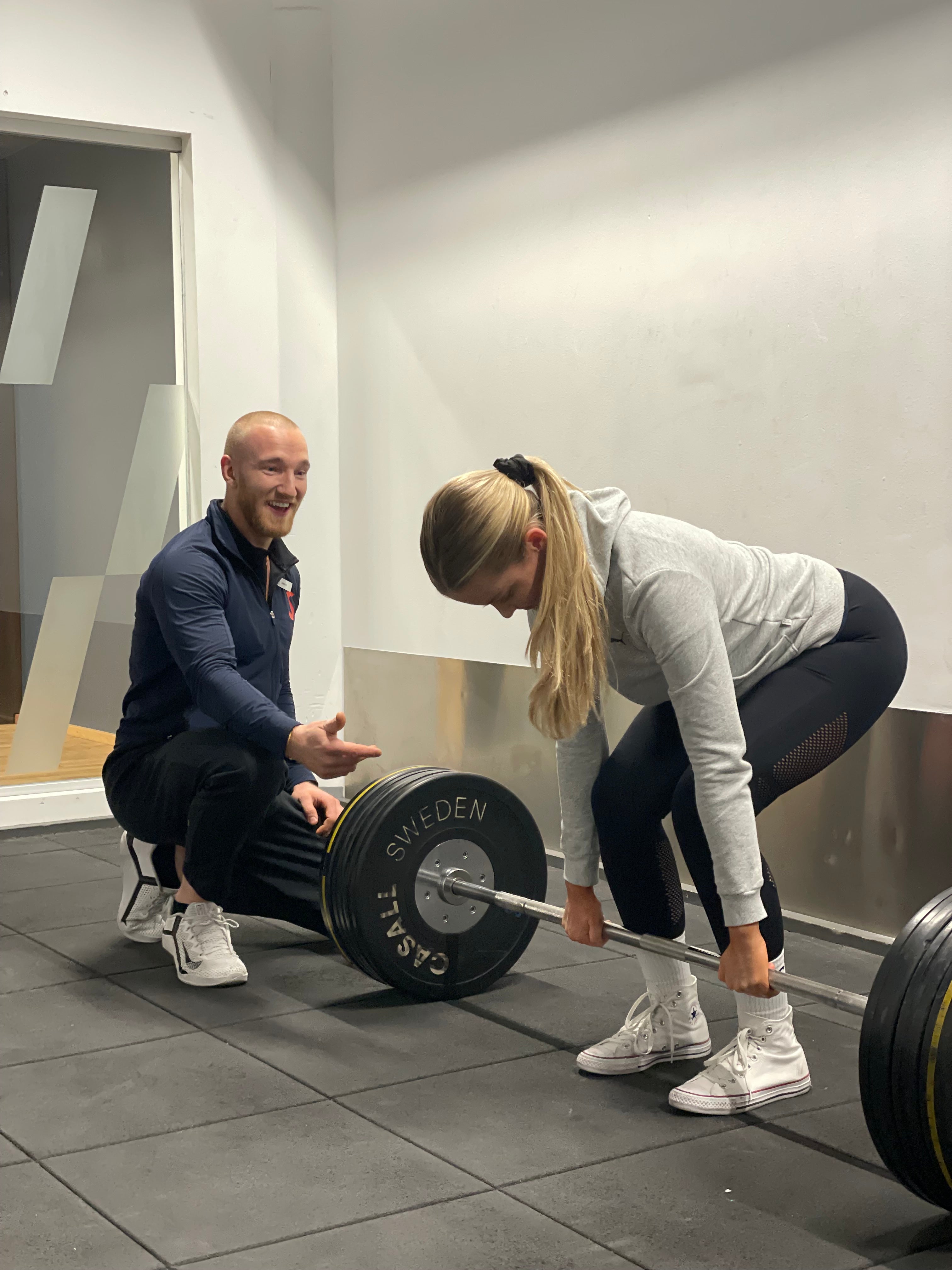 Simon Sundqvist, PT coaching a 20 year old girl at the gym while she's lifting weights. 